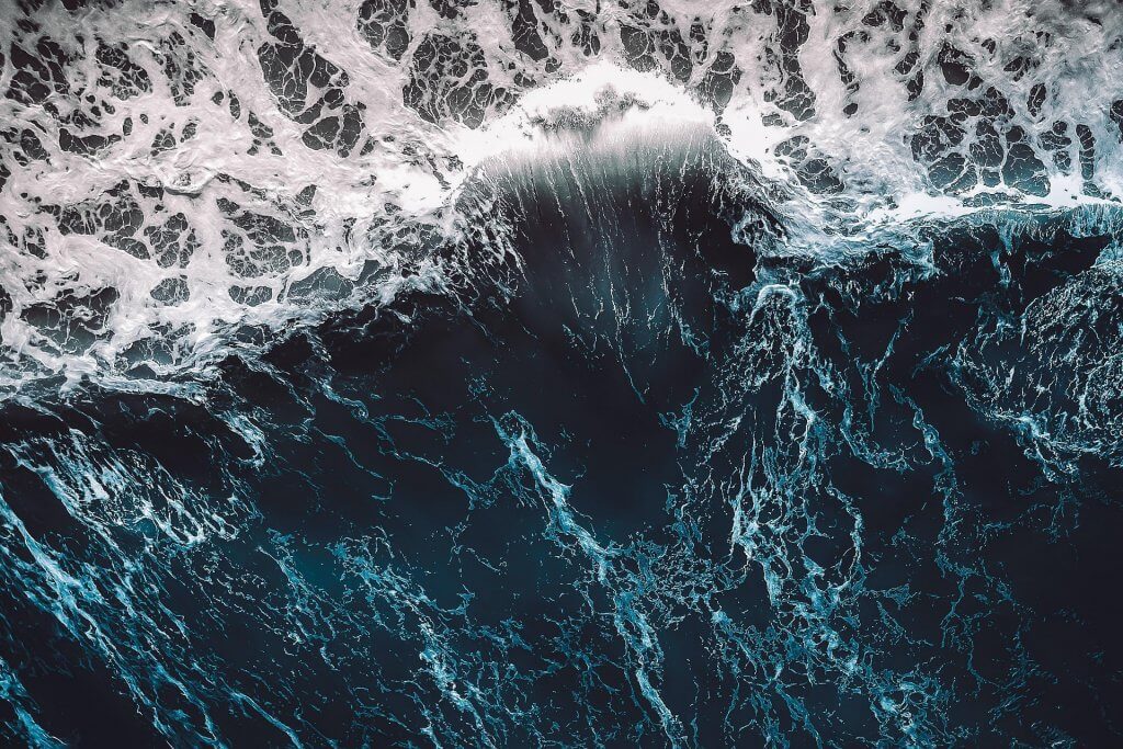 The turbulent ocean with waves and foam is shot from above