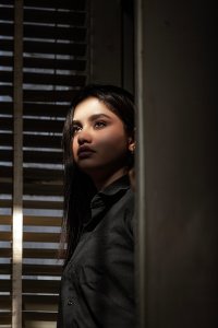 Woman is standing at the window lost in thought and the sun is shining in her face